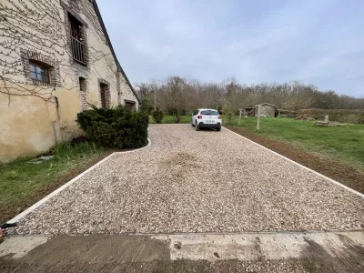 Allée en gravier aménagée devant une maison en pierre